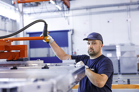 Leadec employee working on a contraption for handling batteries.